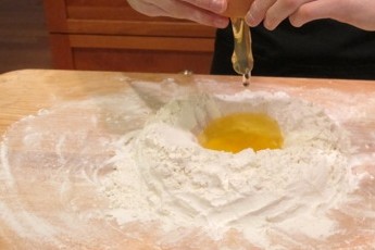 The eggs are cracked over the flour's hole. 