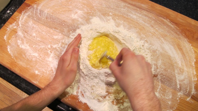 The eggs are beaten in the flour nest, while a little bit of the surrounding flour is added at a time. 